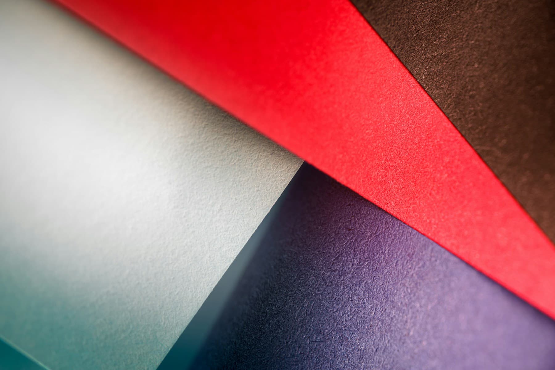 Close-up of layered paper in saturated red, blue, and violet tones.