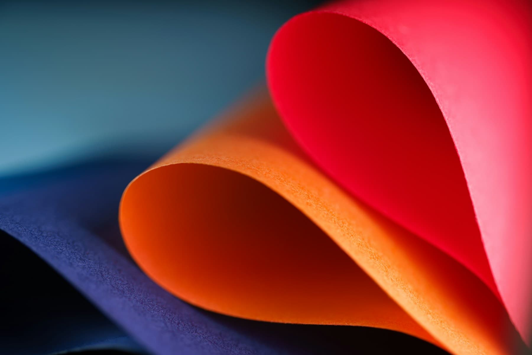 Layered curved paper shapes in orange, blue, pink, and red.